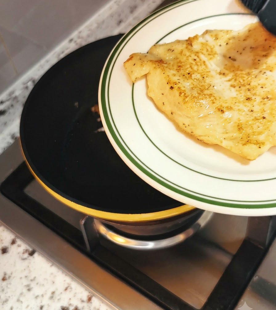 Water being poured into a frying pan around a cooking egg before covering with a lid.