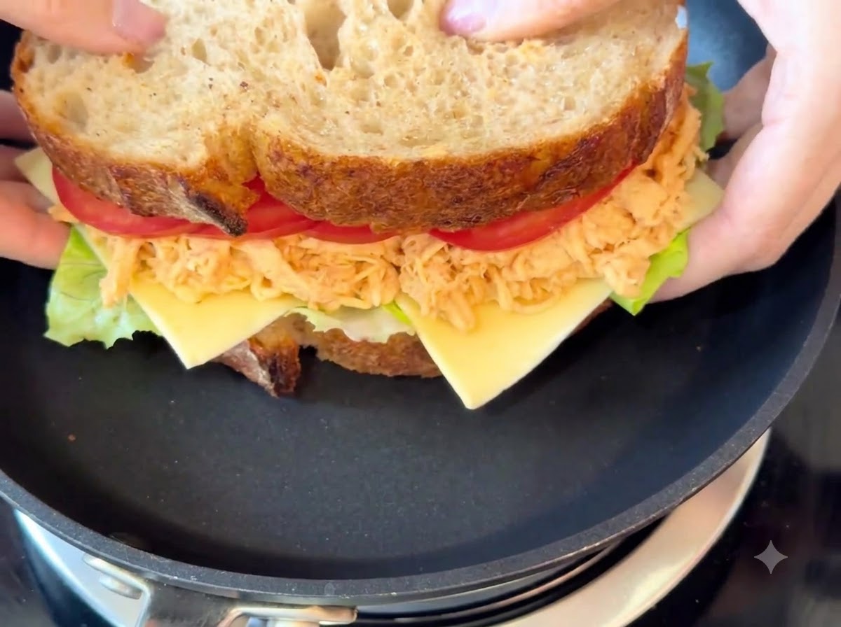 The complete sandwich cooking in a black frying pan over low heat.