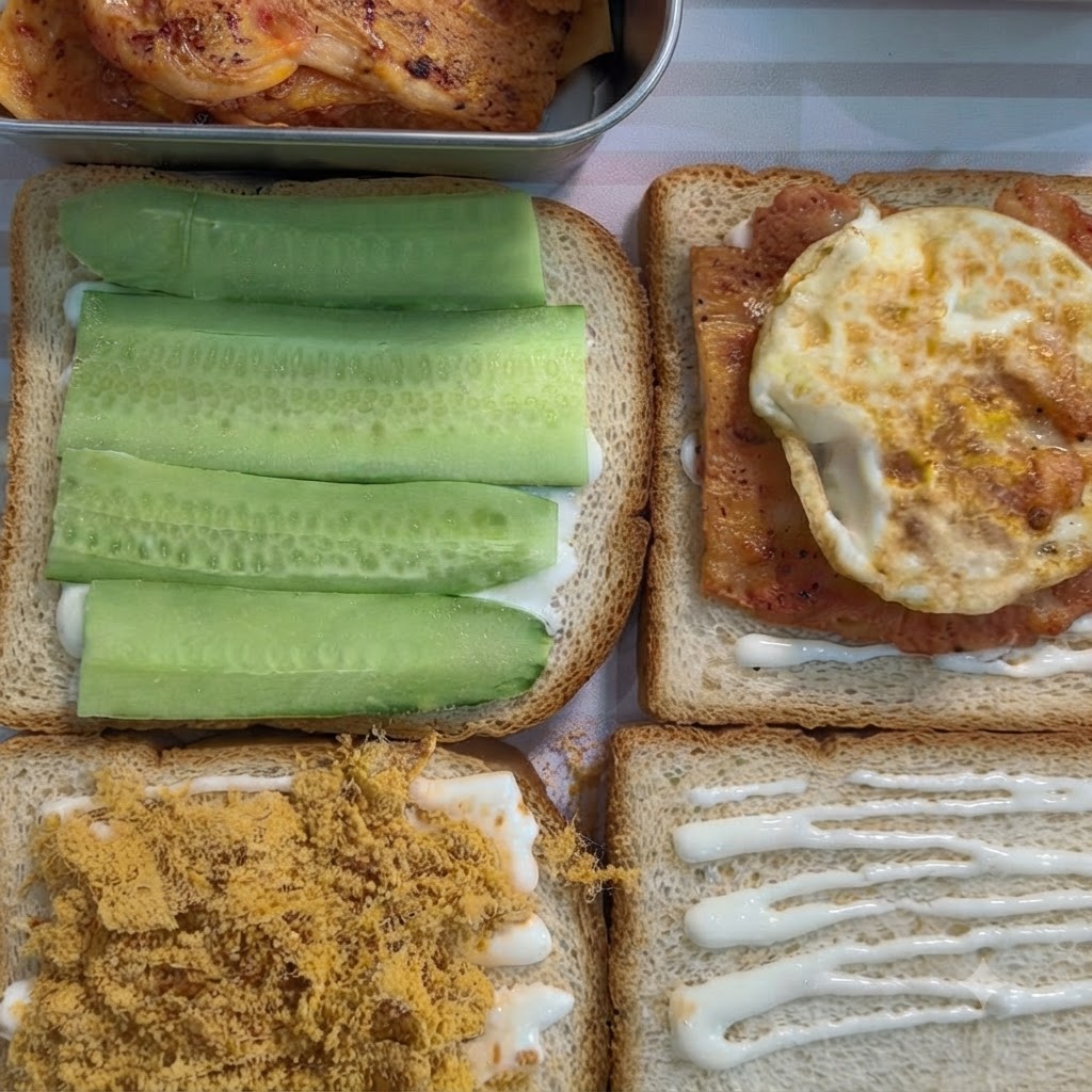 A slice of sandwich bread with white spread topped with a cooked piece of seasoned chicken and a fried egg.