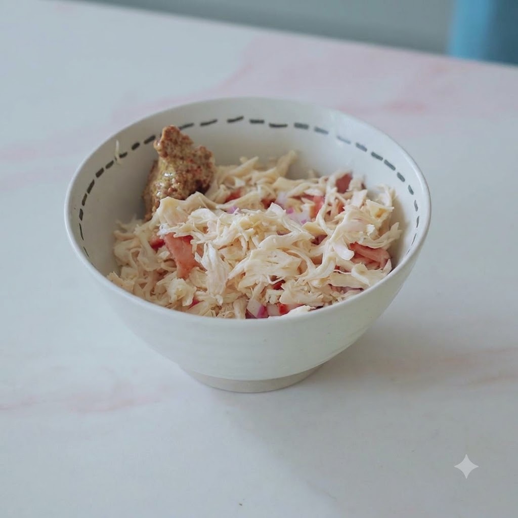 A bowl filled with shredded chicken, bacon, onions, and a dollop of mustard ready to be mixed.