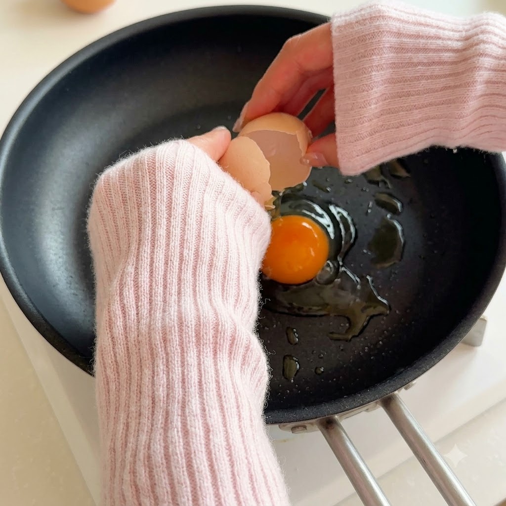 An egg cracking into a hot skillet with oil.
