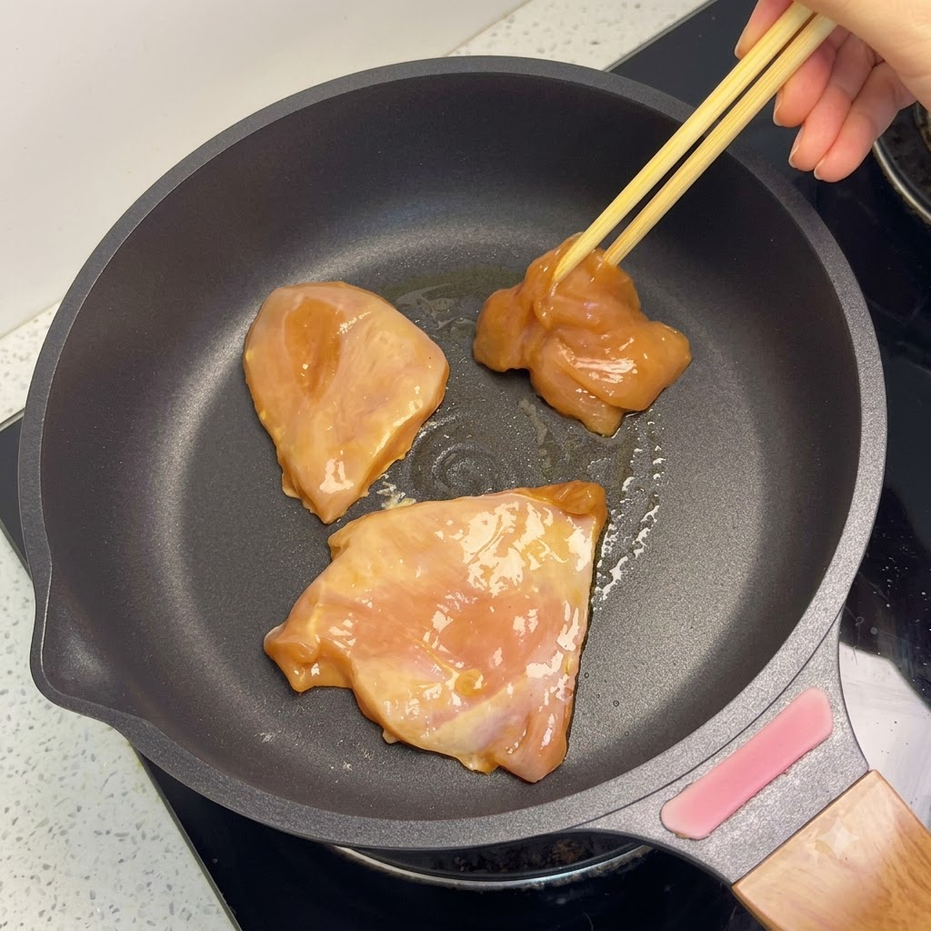 Golden-brown chicken breast pieces cooking in a skillet.