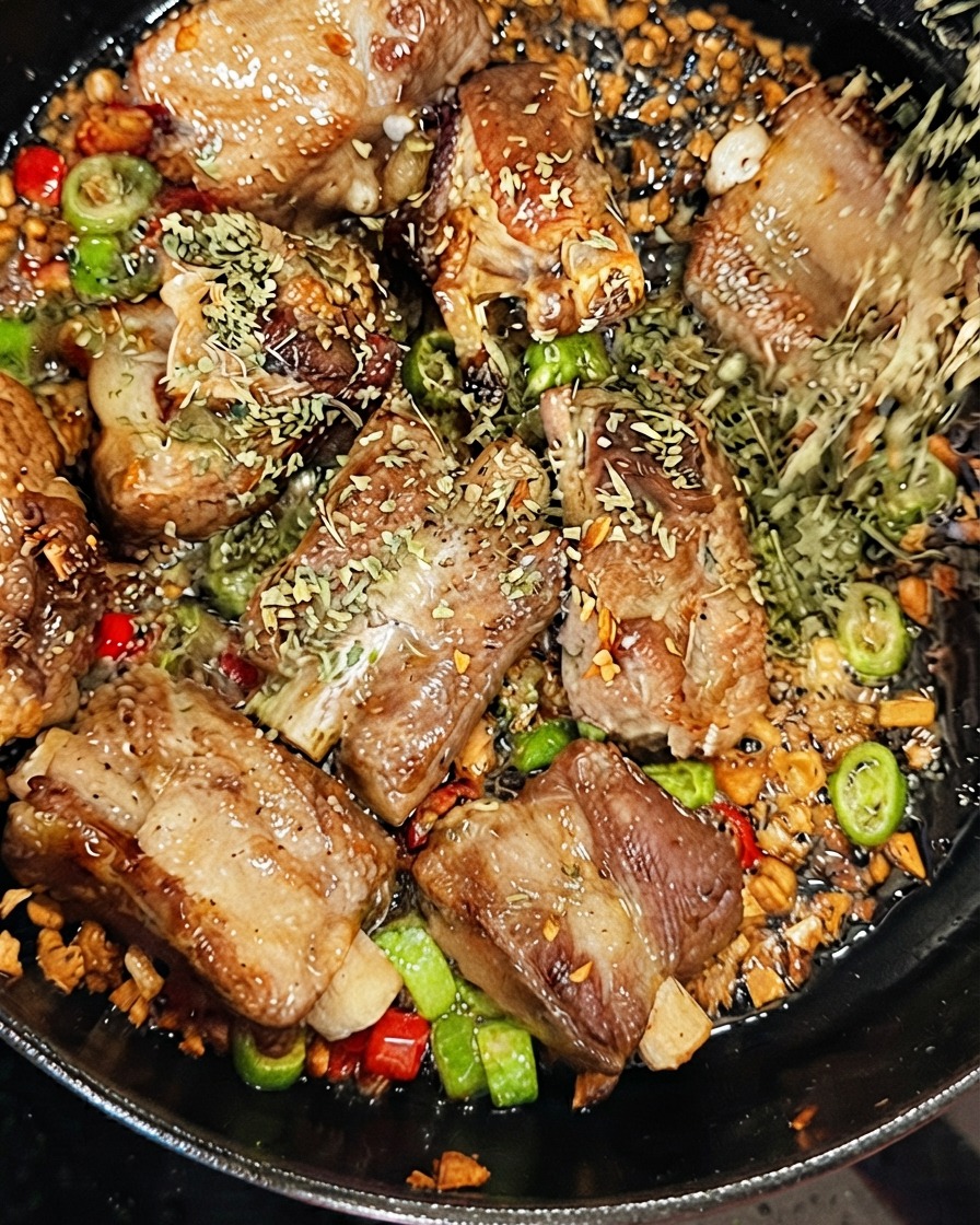 Dried parsley being sprinkled onto pork ribs while dry white wine is poured into the sizzling pan.