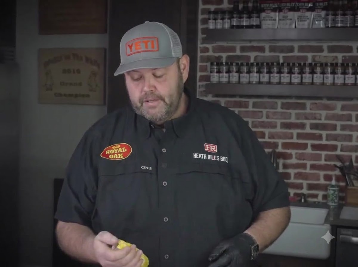 A chef holding a yellow mustard bottle while preparing ribs in a kitchen.