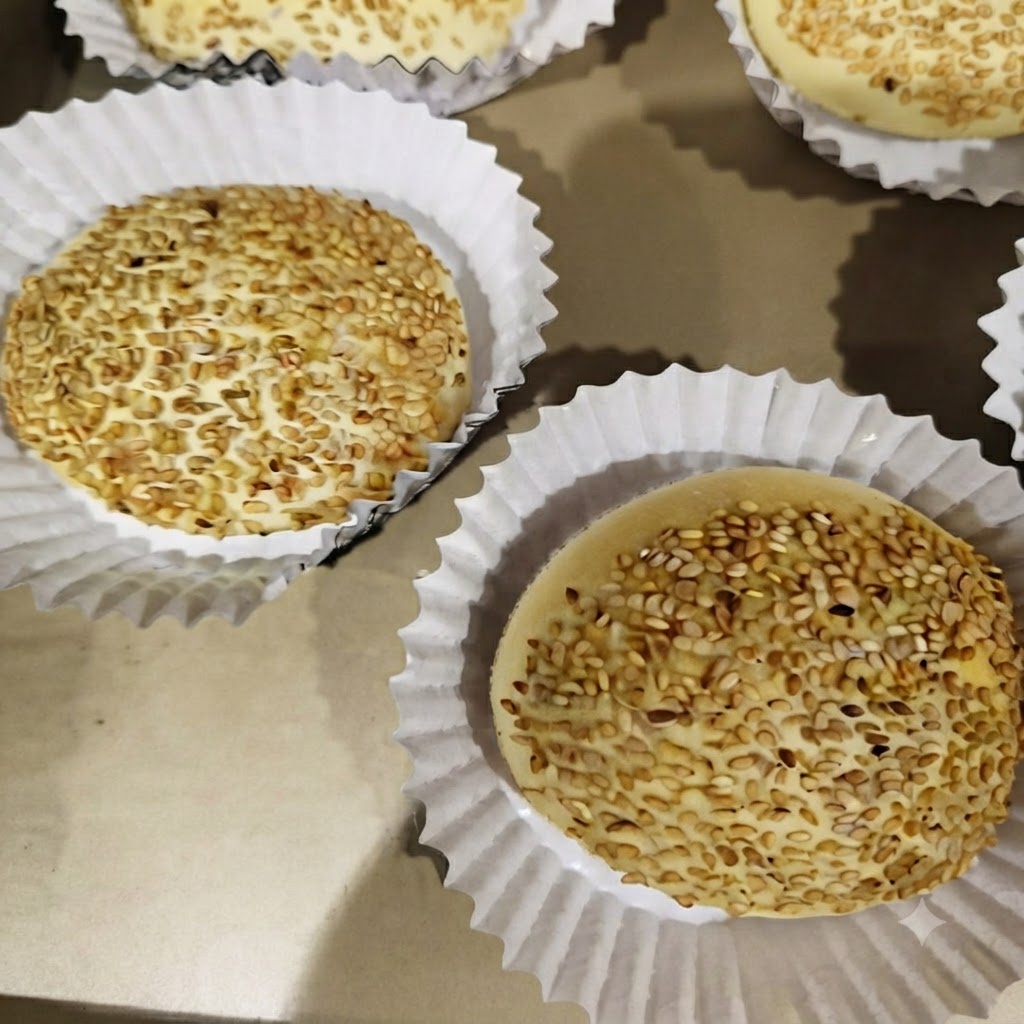 Burger patties cooking in individual sections of a four-compartment pan on a stove.
