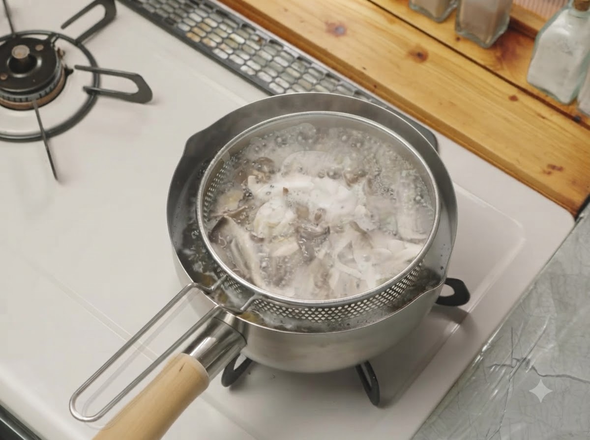 Torn mushrooms boiling inside a mesh strainer basket placed inside a pot of water on the stove.