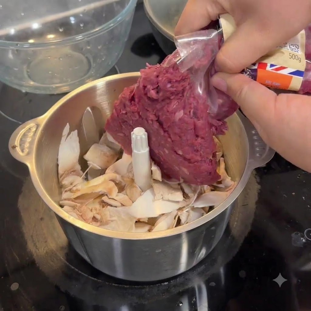 Hands squeezing raw ground beef from a plastic package into a steel food processor bowl filled with mushroom pieces.