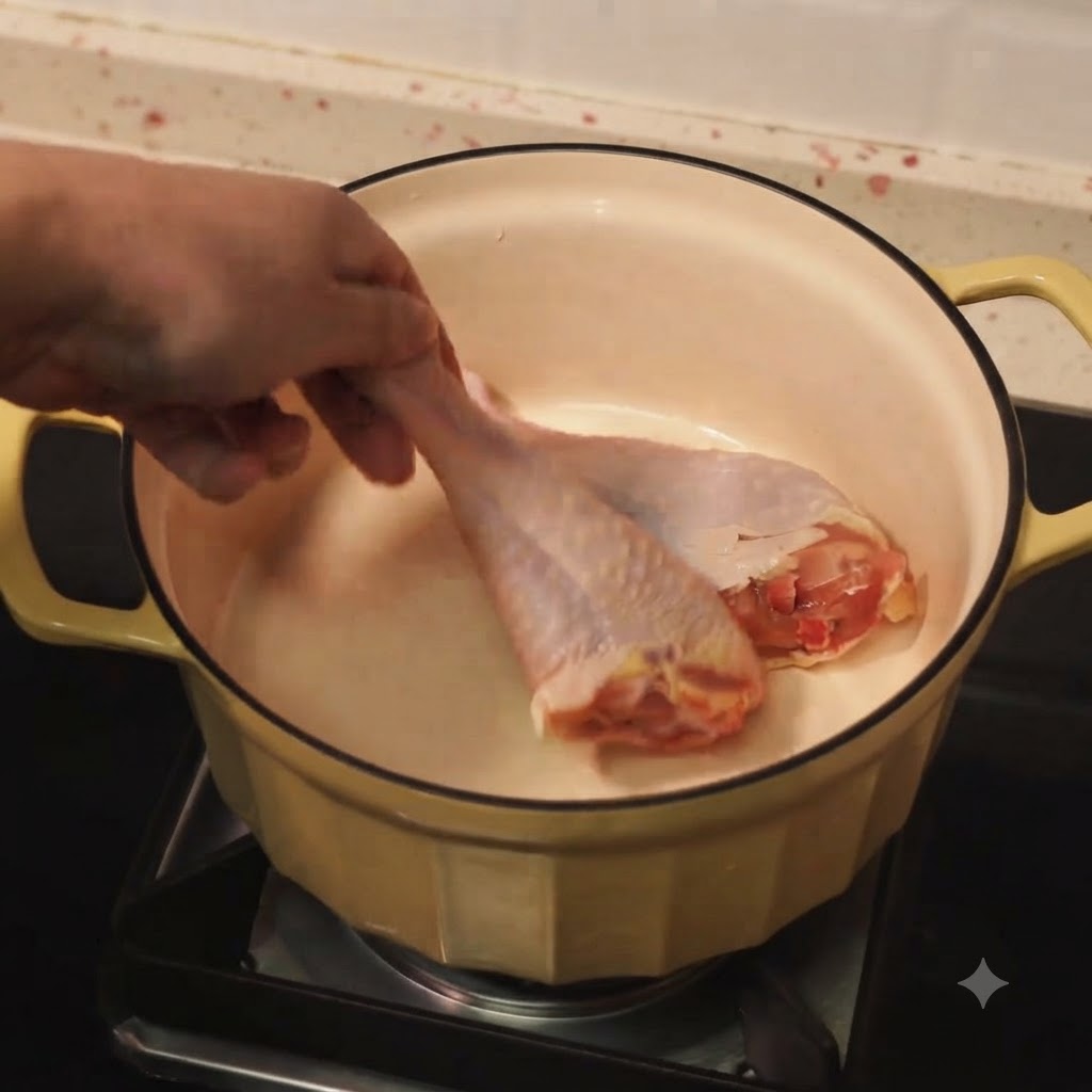 Chicken drumsticks browning in a pot with hot oil.