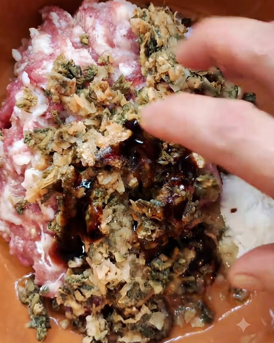 A hand combining minced pork, chopped preserved mustard greens, and seasonings in a brown bowl.