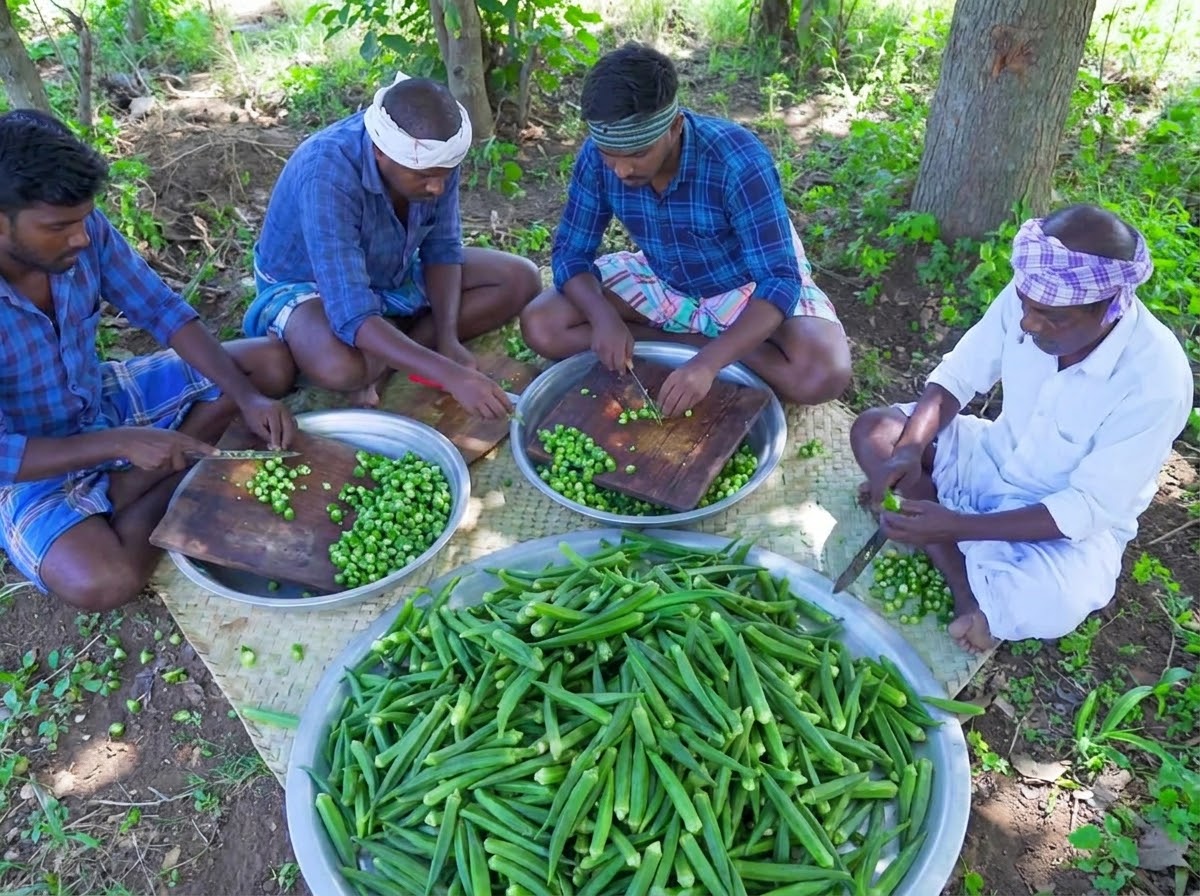 Multiple people sitting and chopping raw green okra on wooden cutting boards.