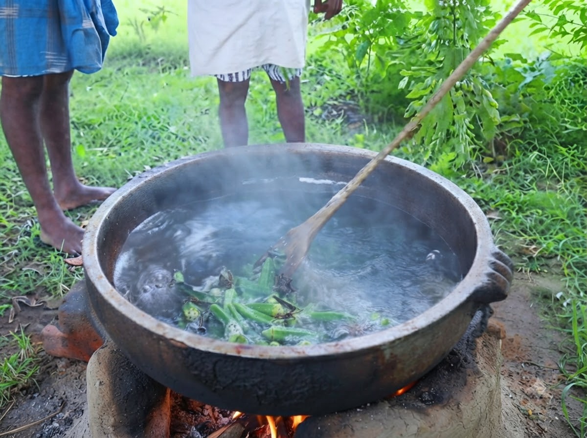 Fresh green curry leaves being stripped directly from a branch into a simmering pot of seasoned oil outdoors.