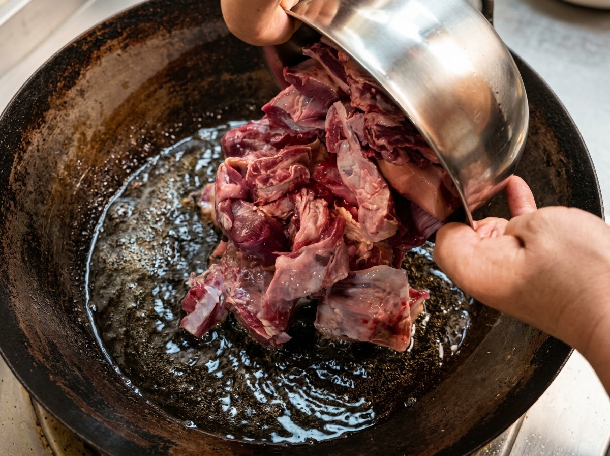 Large chunks of beef brisket being added to water in a wok.