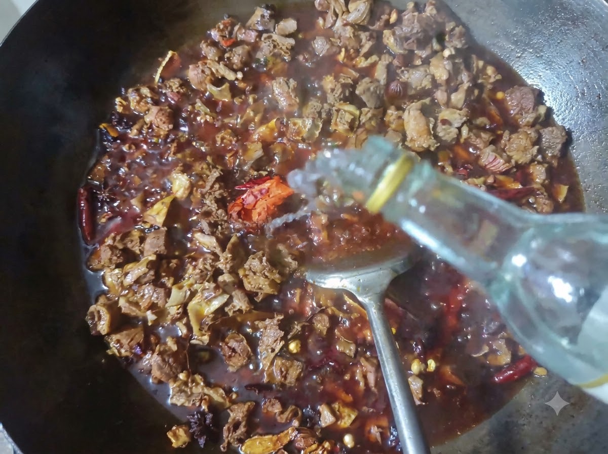 A bottle pouring clear baijiu into a wok filled with braising beef and spices.