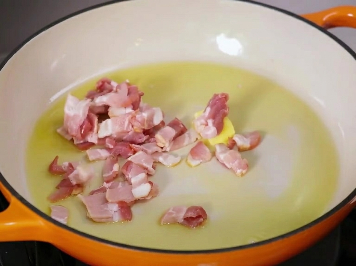 Bacon pieces sizzling in a pan with melted butter and olive oil.