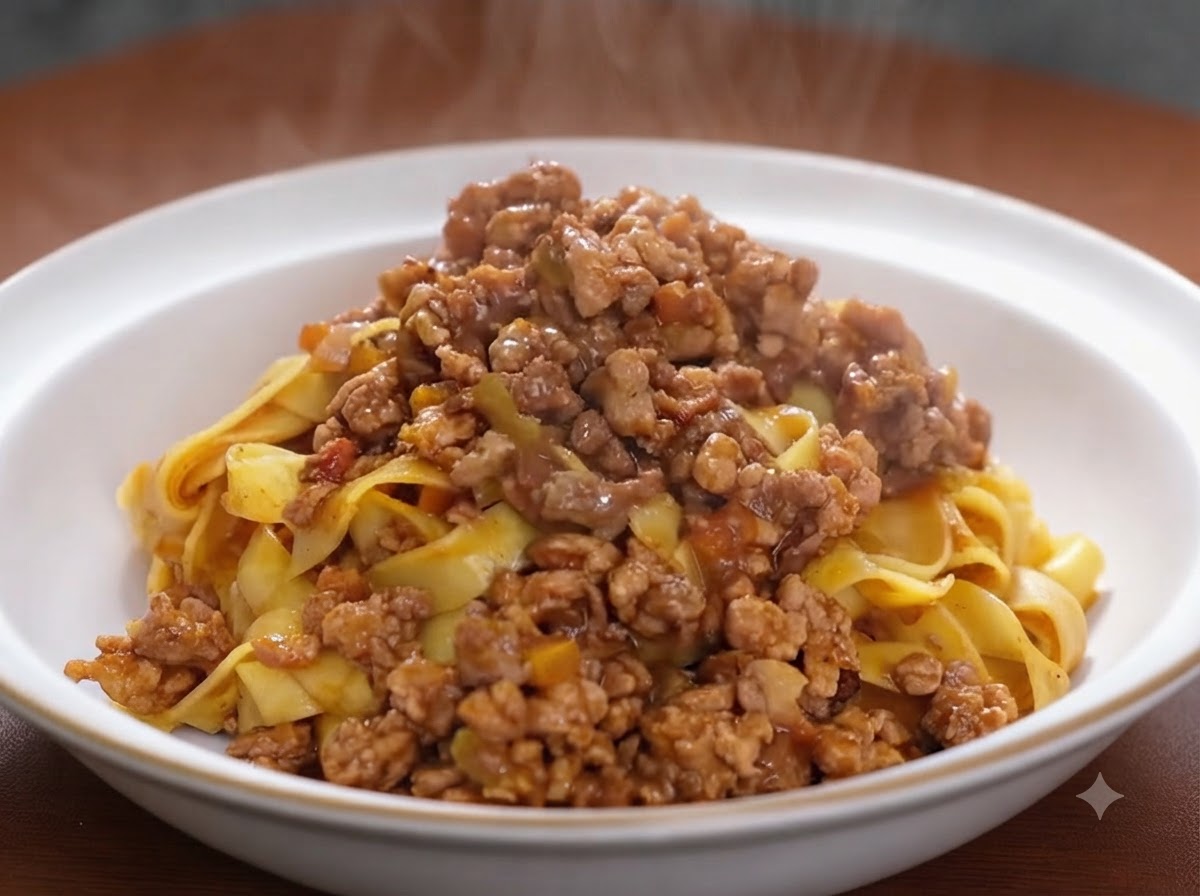Tomato paste being combined into a browned meat and vegetable mixture in a cooking pan.