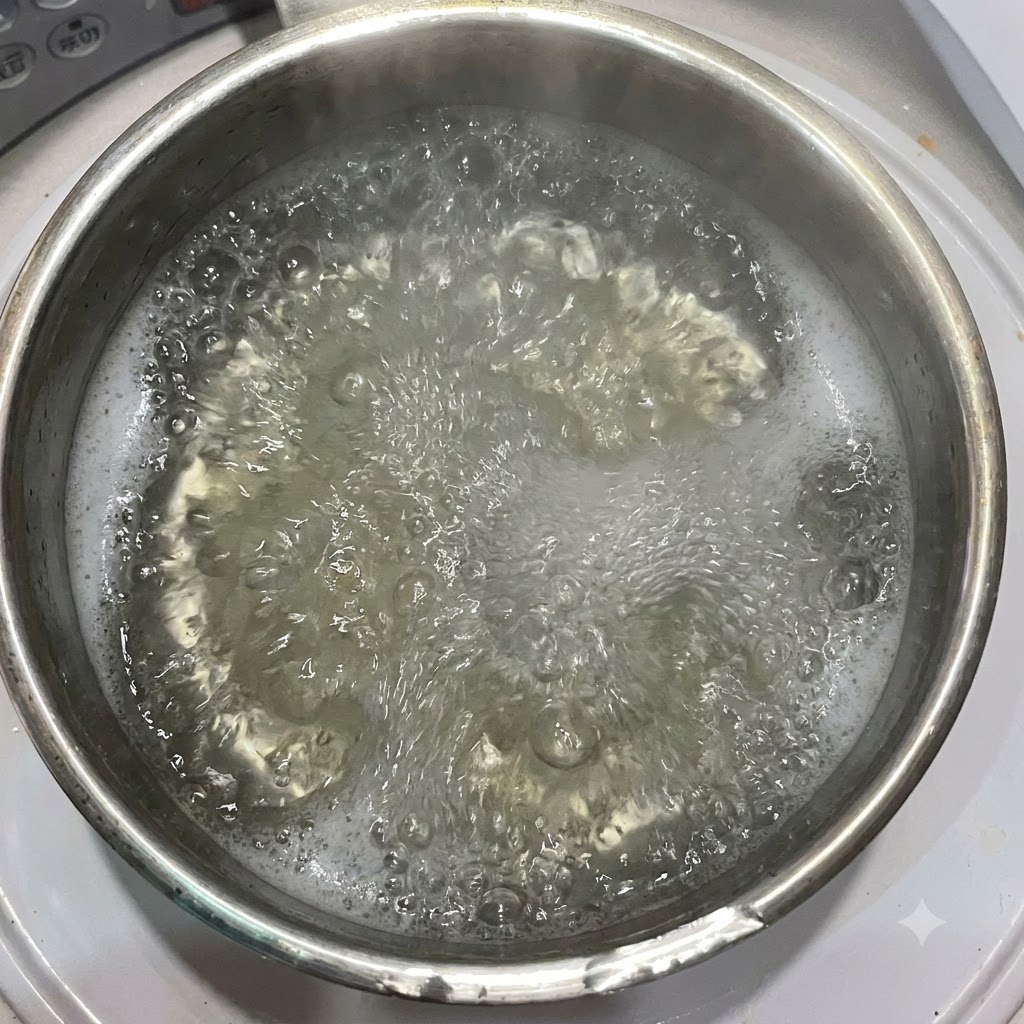 Olive oil being poured into a pot of boiling water containing penne pasta.