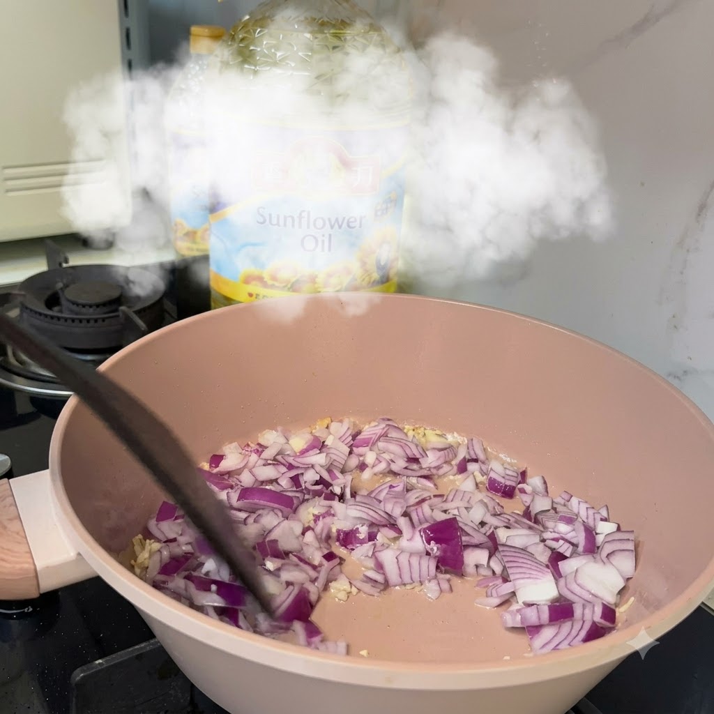 Diced red onions cooking in a pan with garlic and oil over a stove.