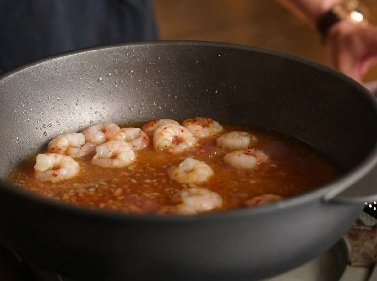 Spaghetti noodles mixed into the pan with shrimp, broth, and sauce.