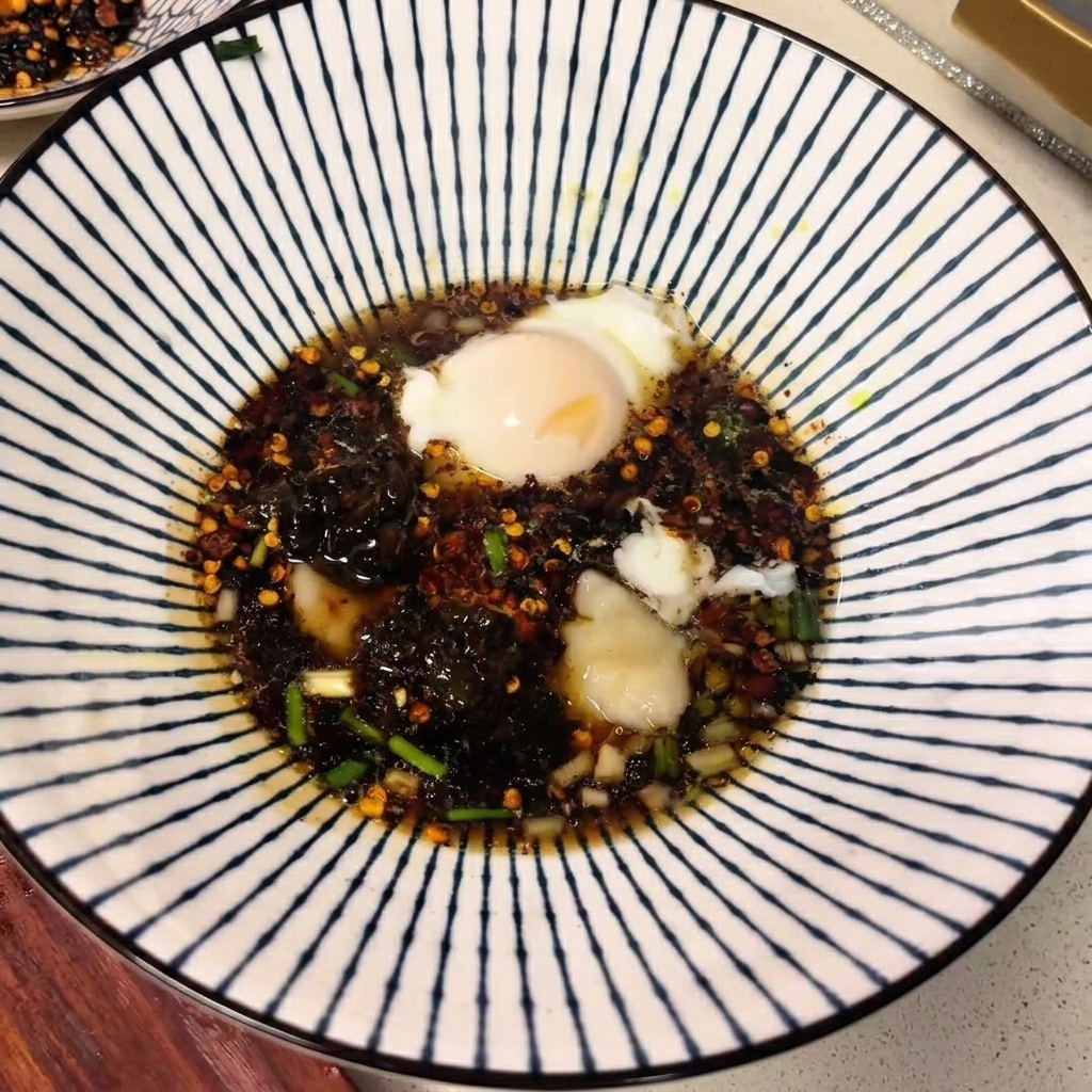 A ceramic bowl filled with dark soup broth, spices, and a poached egg floating on top.
