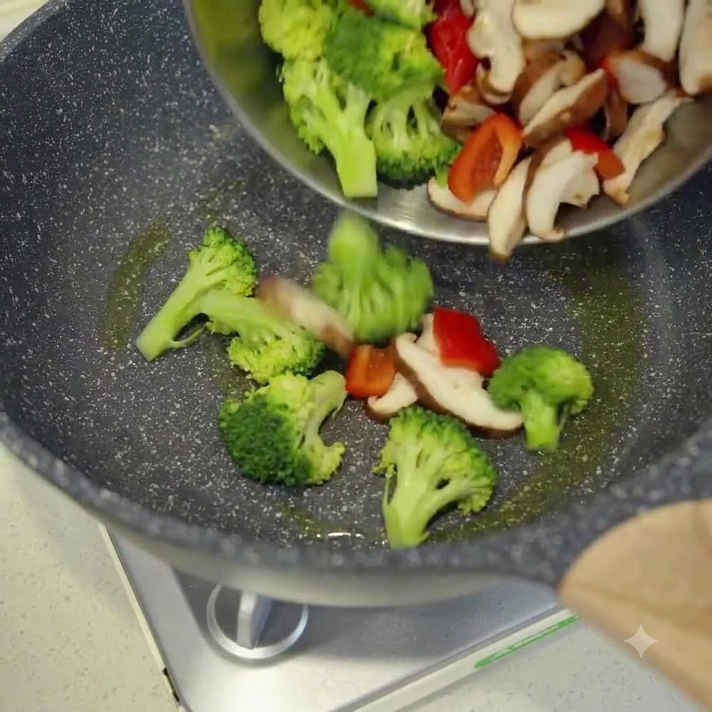 Freshly sliced vegetables being poured from a bowl into a hot oiled wok.