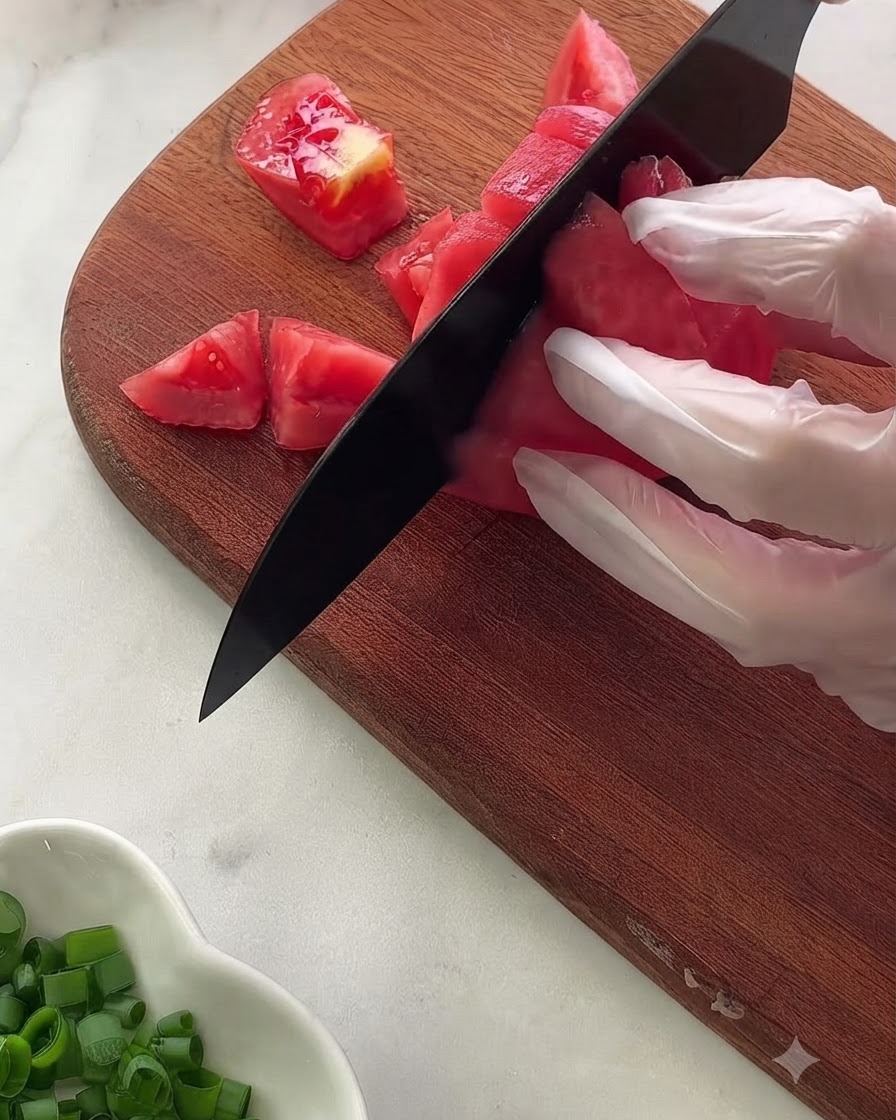 A close-up view of various sauce ingredients and seasonings measured inside a glass bowl resting on a polka-dot cloth.