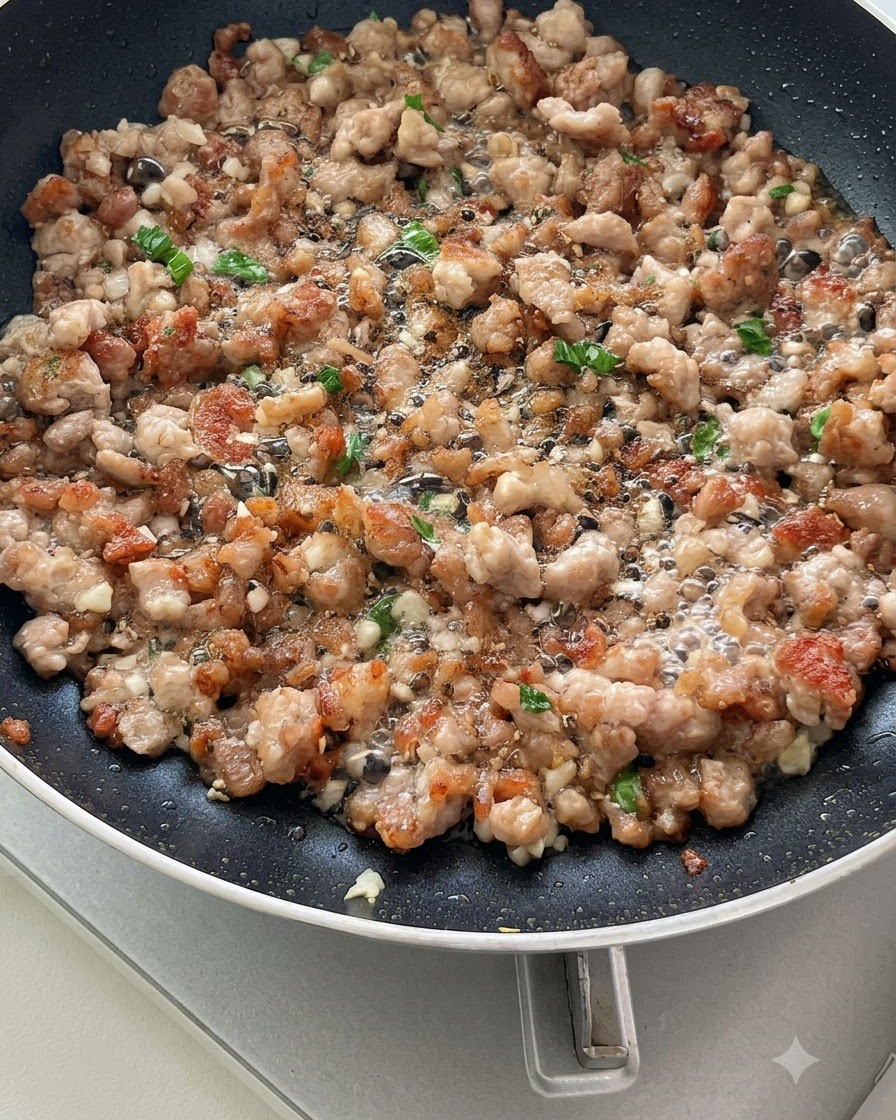 Sliced tomatoes being stir-fried with ground meat and aromatics in a pan, starting to release juices.