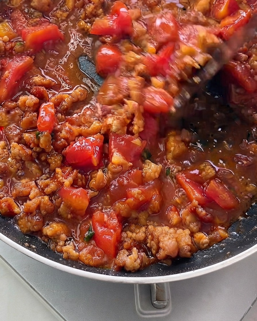 The sauce mixture simmering and thickening inside a skillet.