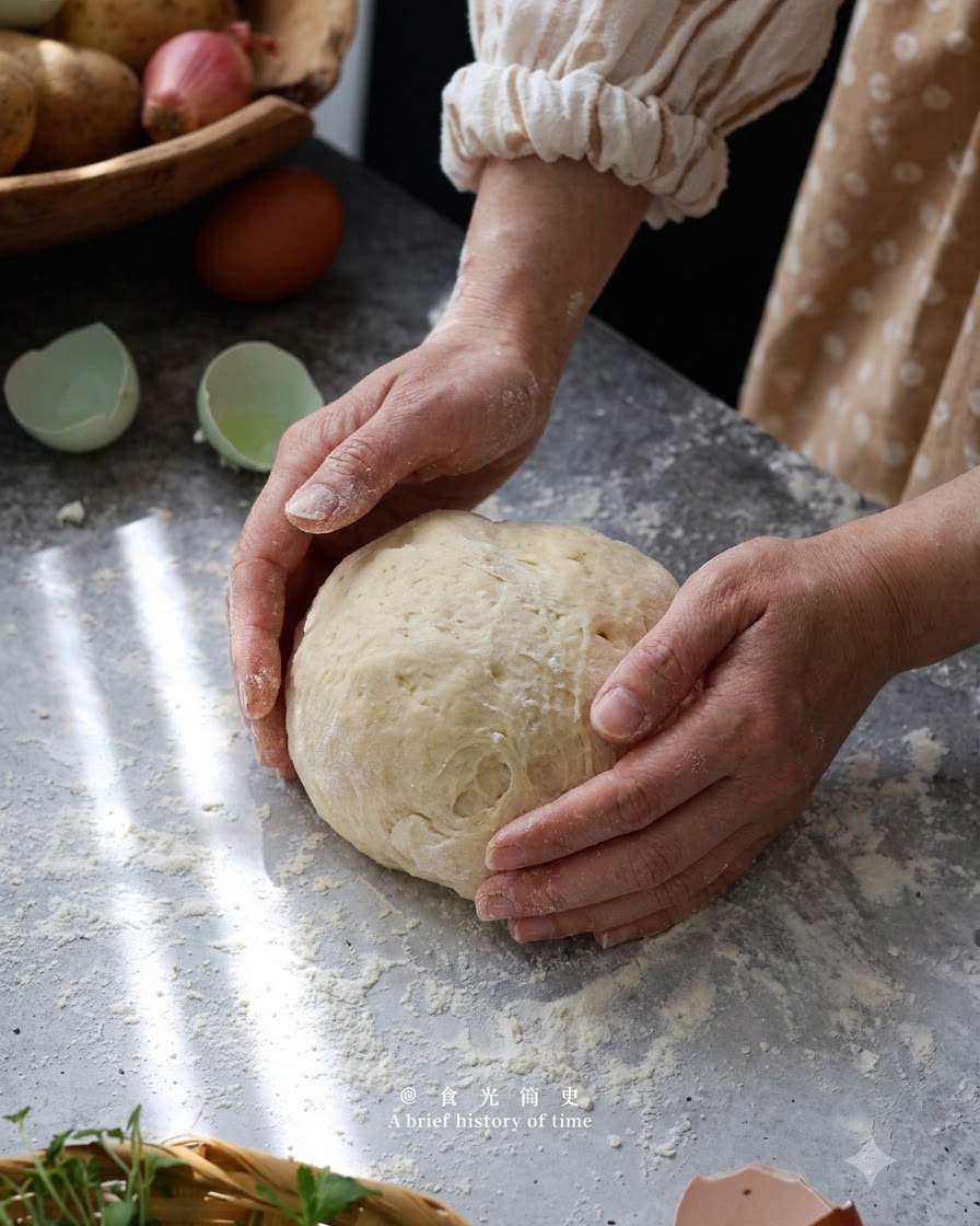 Hands gently forming and kneading potato gnocchi dough into a ball on a floured surface.