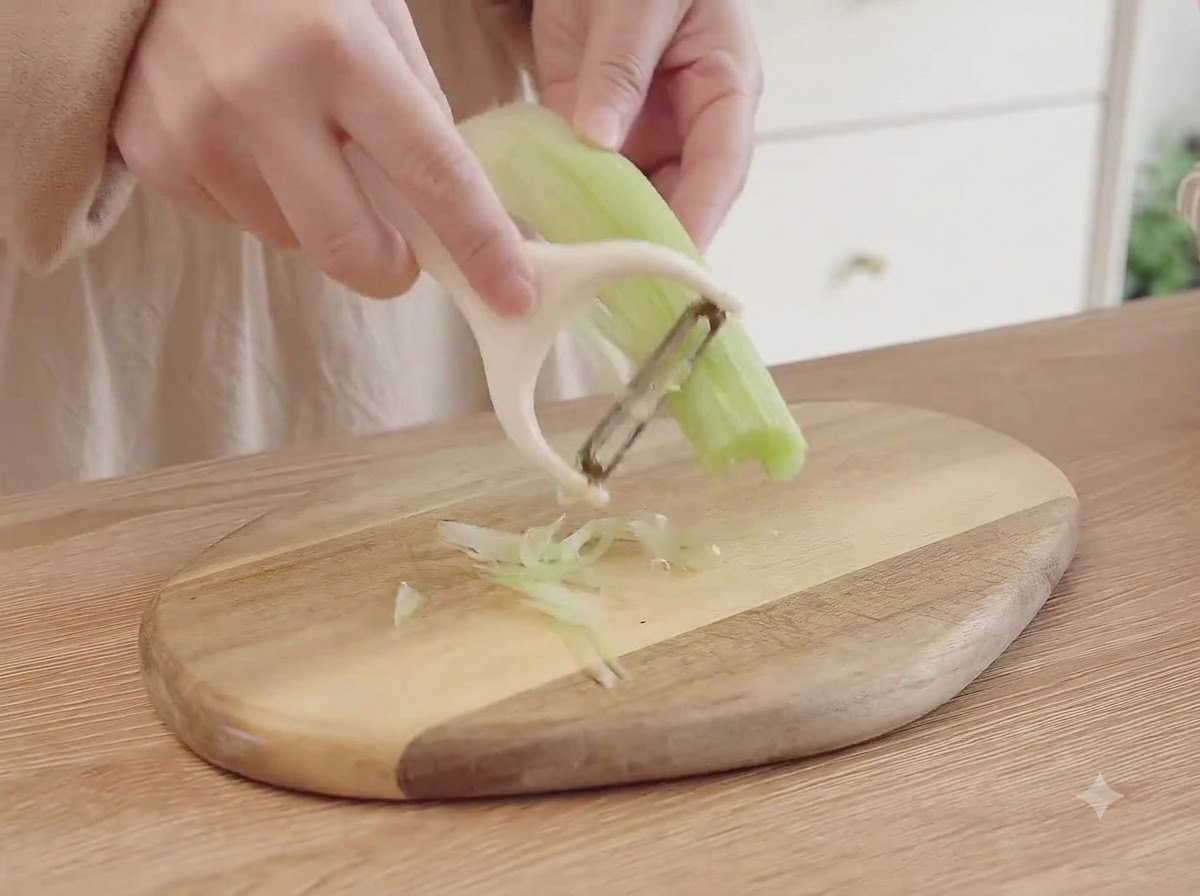 Celery, carrots, and onions being finely diced into small pieces on a wooden cutting board.