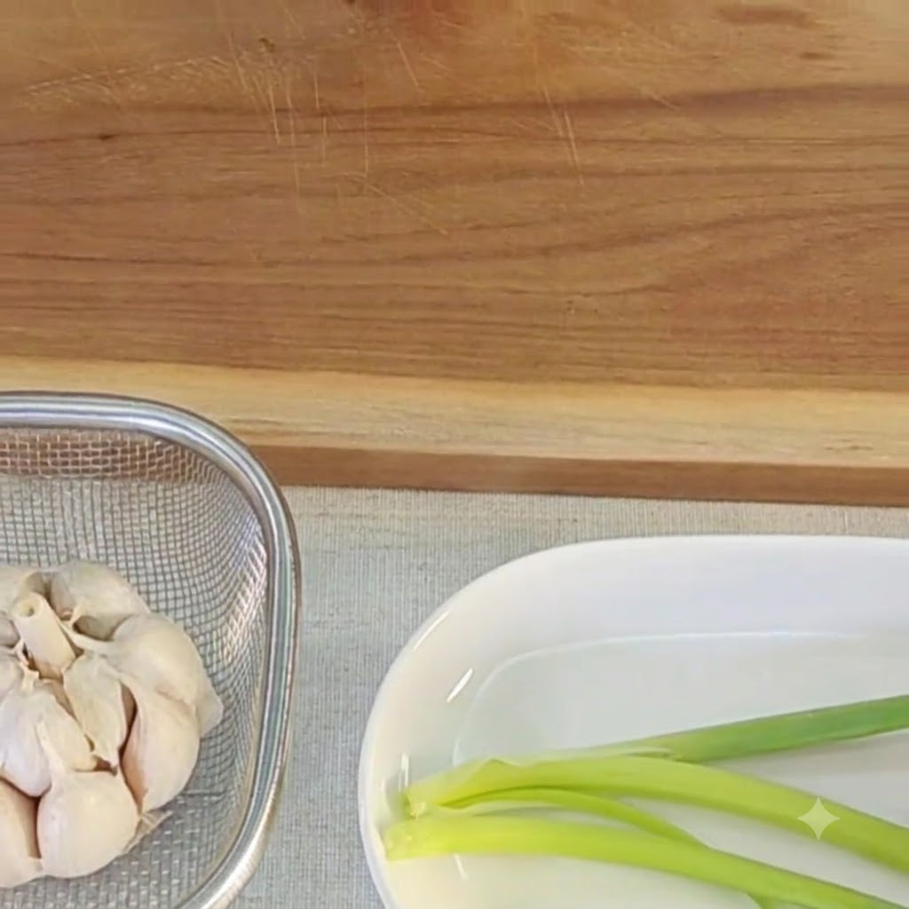 Garlic bulb being sliced on a wooden board with a knife.