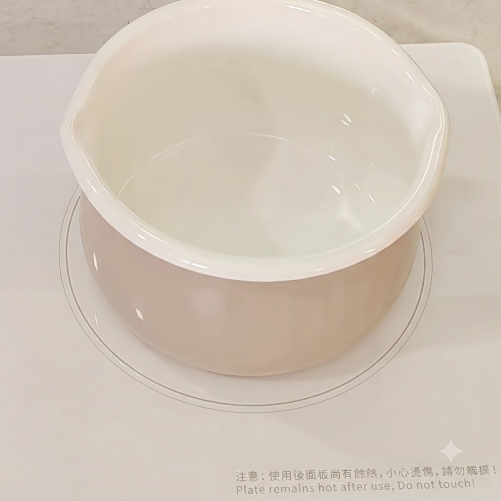 Water poured into a white cooking pot on a stove.