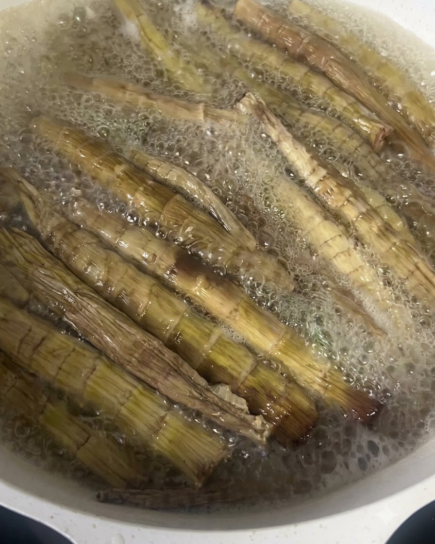 Dried bamboo shoots boiling vigorously in a pan of hot water.