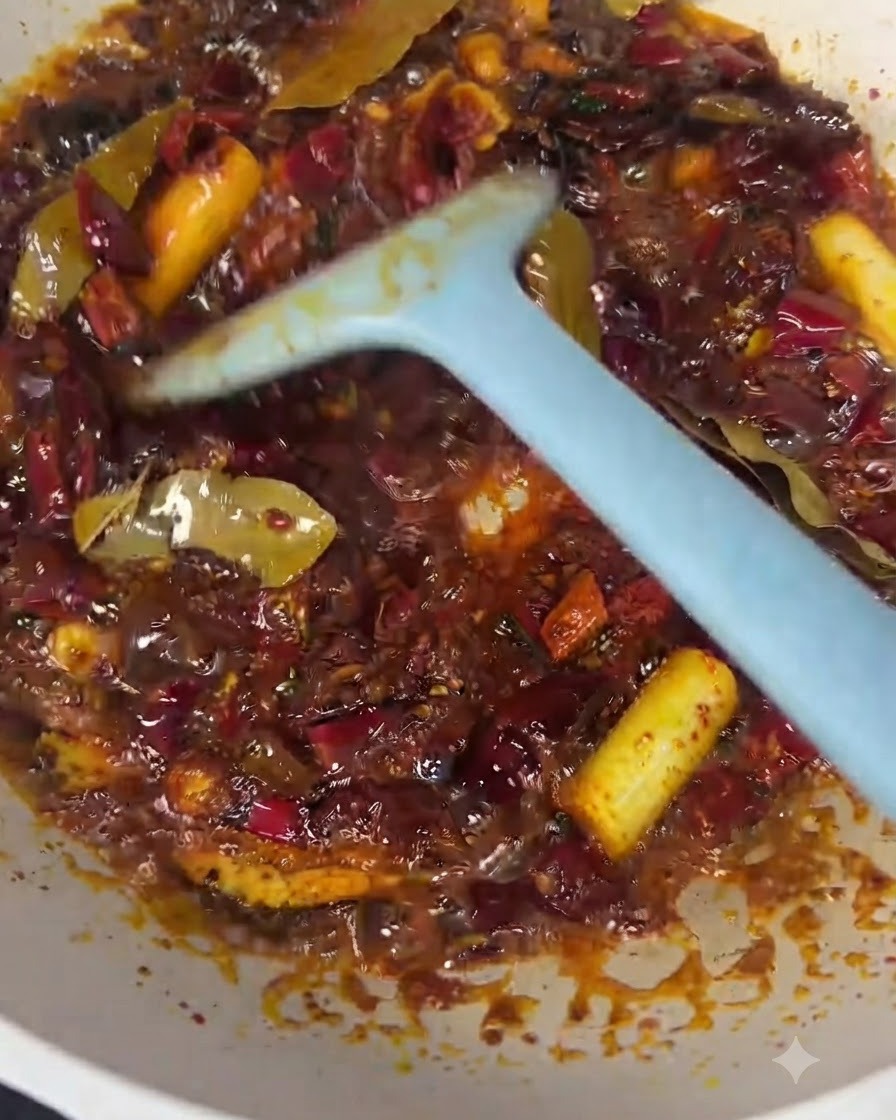 Beef chunks being mixed into the red chili oil and spice base with a blue spatula.