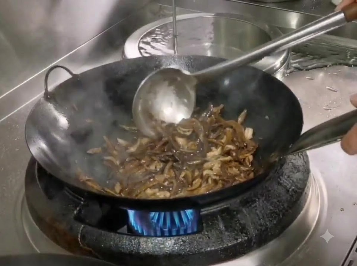 Salt and sugar being stirred into the wok with bamboo shoots and shredded pork using a metal spatula.