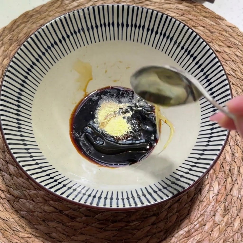 Thick sesame-peanut paste and a drizzle of sesame oil being added into the bowl of seasonings.