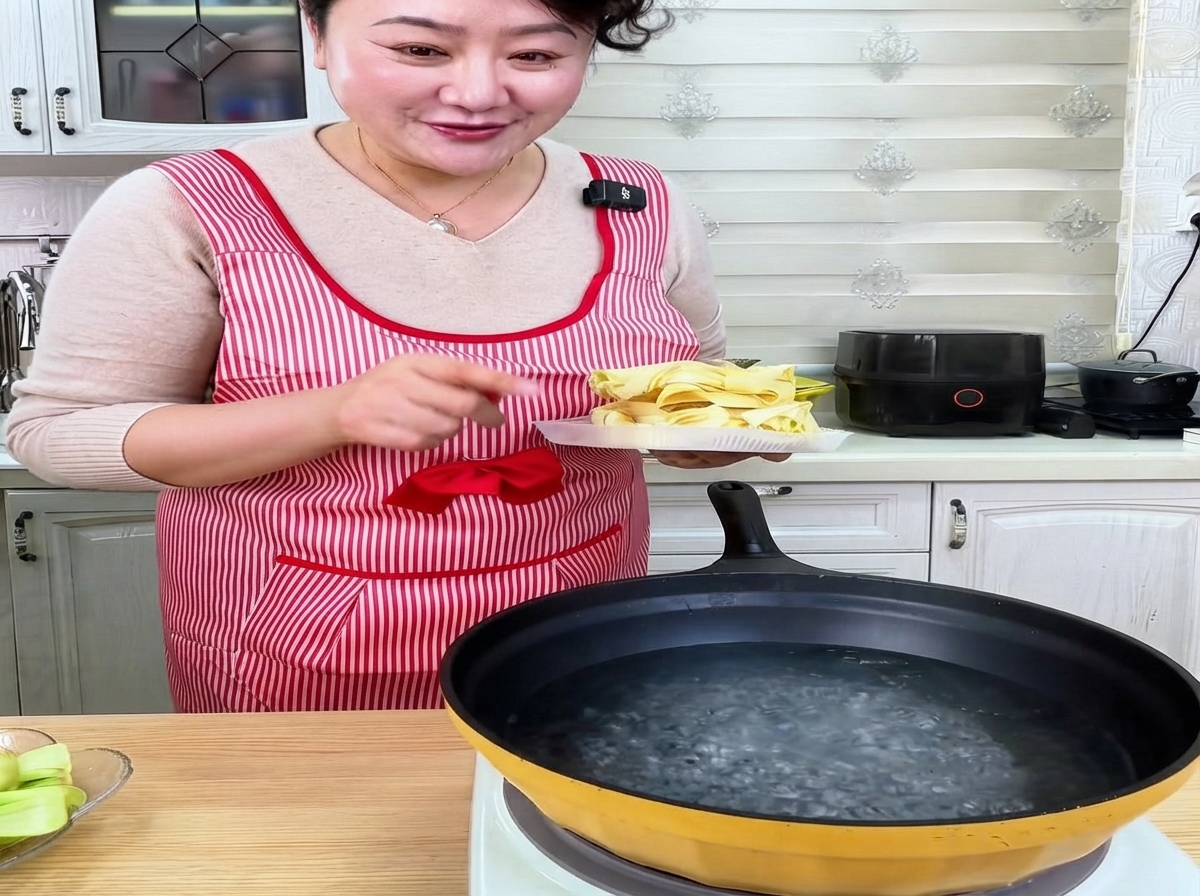 Dried wide wheat noodles being placed into a pan of boiling water.