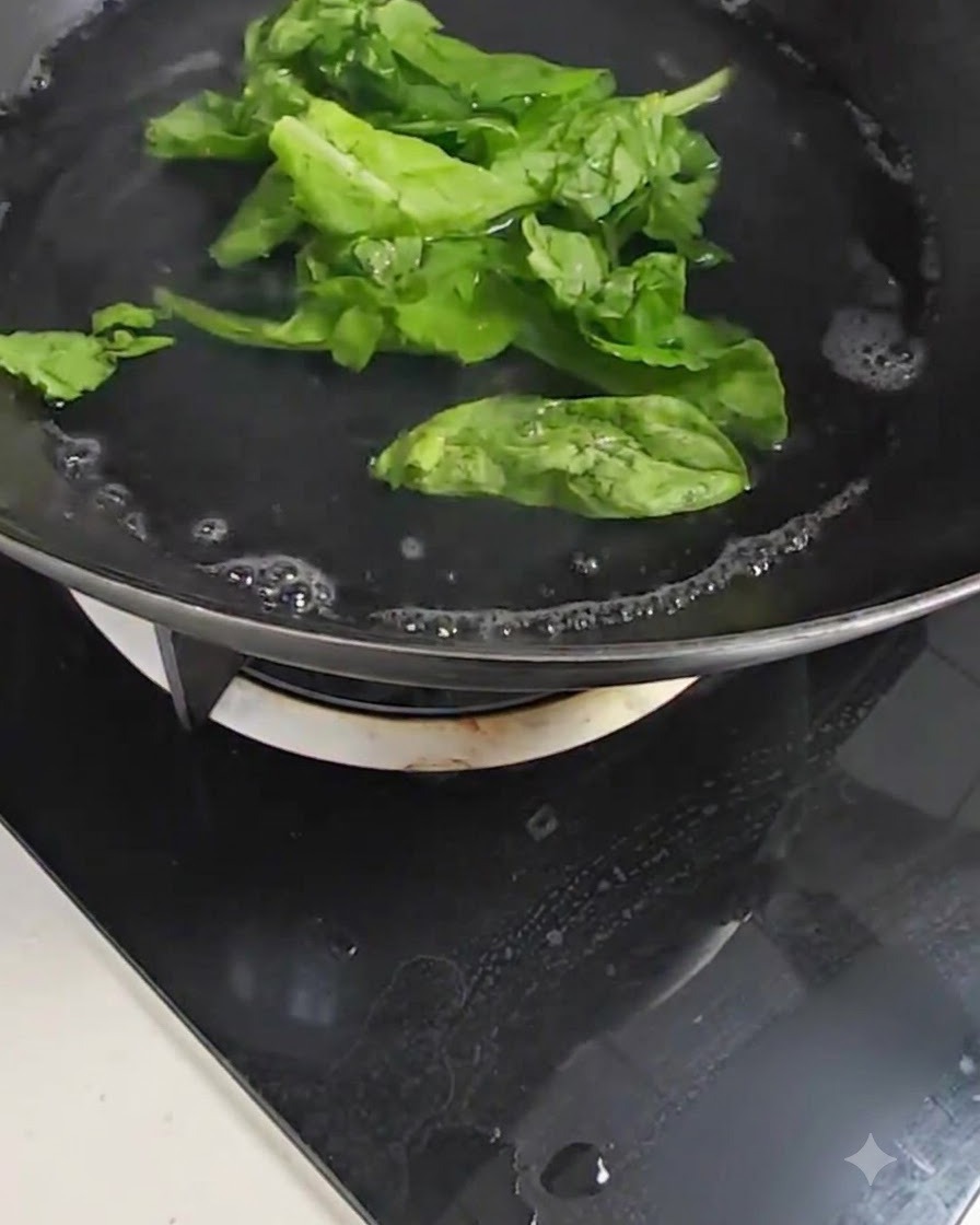 Fresh green bok choy leaves boiling in a pot of bubbling water on a stove.
