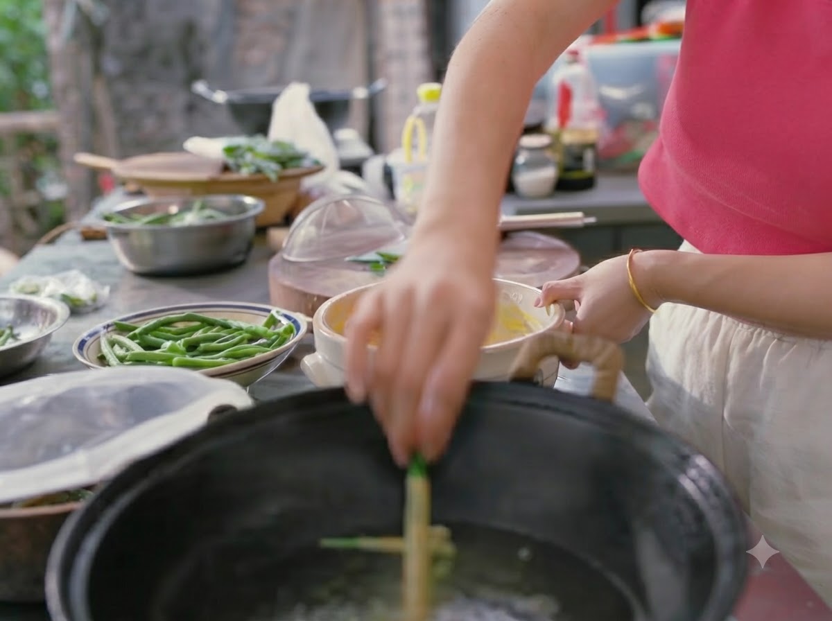 A hand lowering batter-coated green beans into a wok of boiling water.