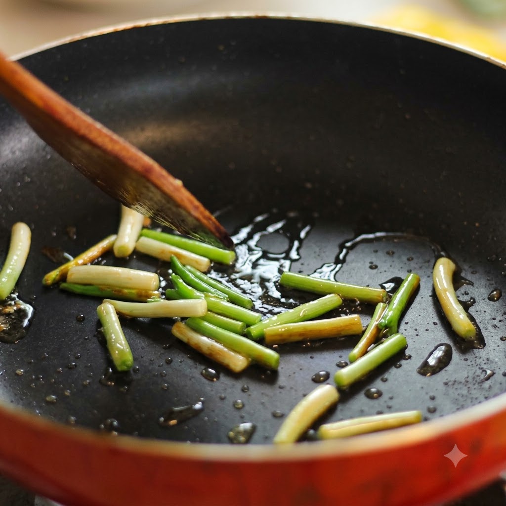 Scallion segments sizzling in a hot oiled frying pan being moved with a wooden spatula.