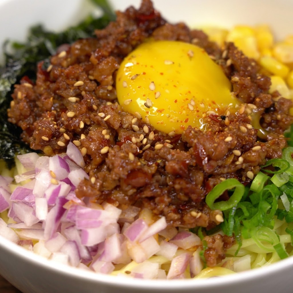 Yellow noodles cooking in boiling water inside a metal pot.