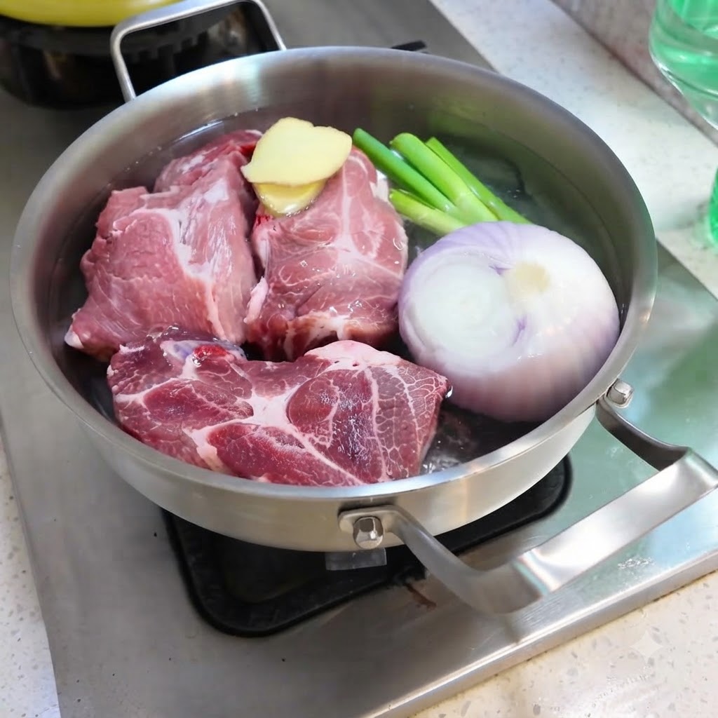 Water being poured into a pan filled with pork, onion, ginger, scallions, and spices.
