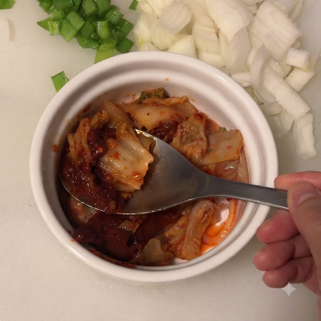 Light soy sauce being added to the bowl containing kimchi and Korean chili paste.