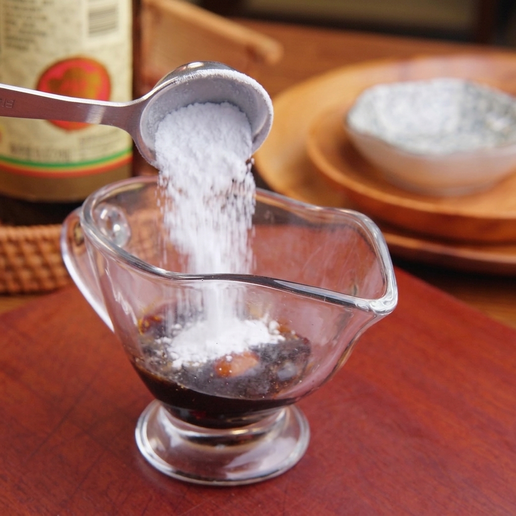 Adding sugar and liquid seasonings into a clear glass container filled with dark soy sauce.
