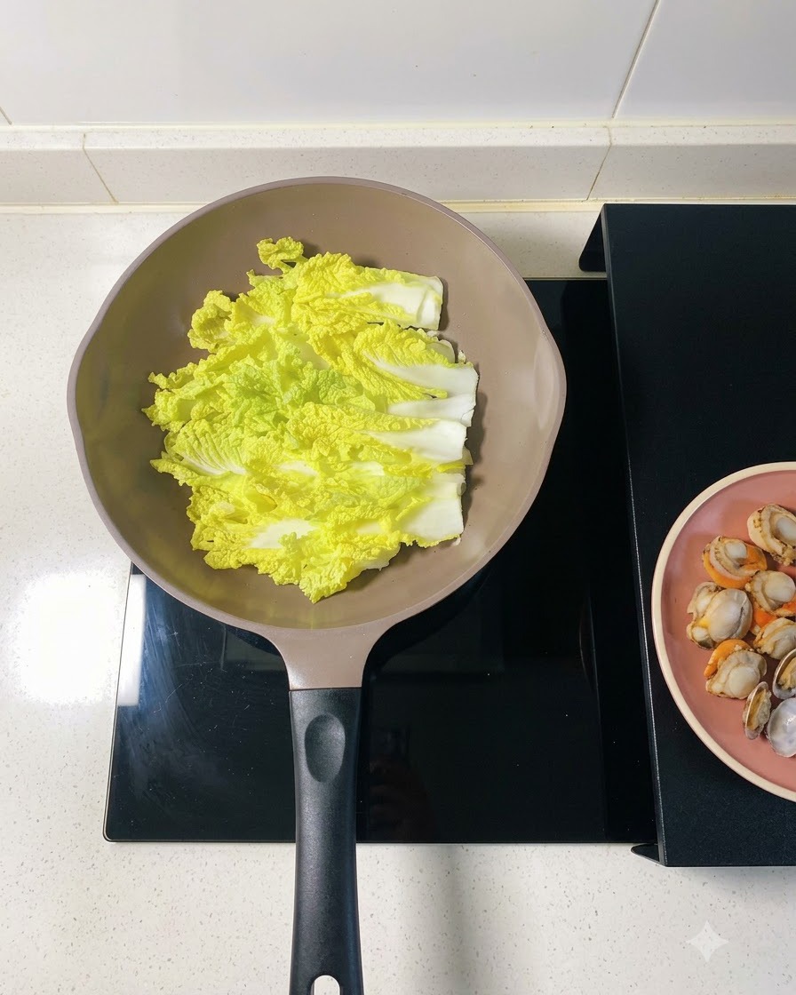 Soaked vermicelli noodles being layered directly over the napa cabbage in the pan.