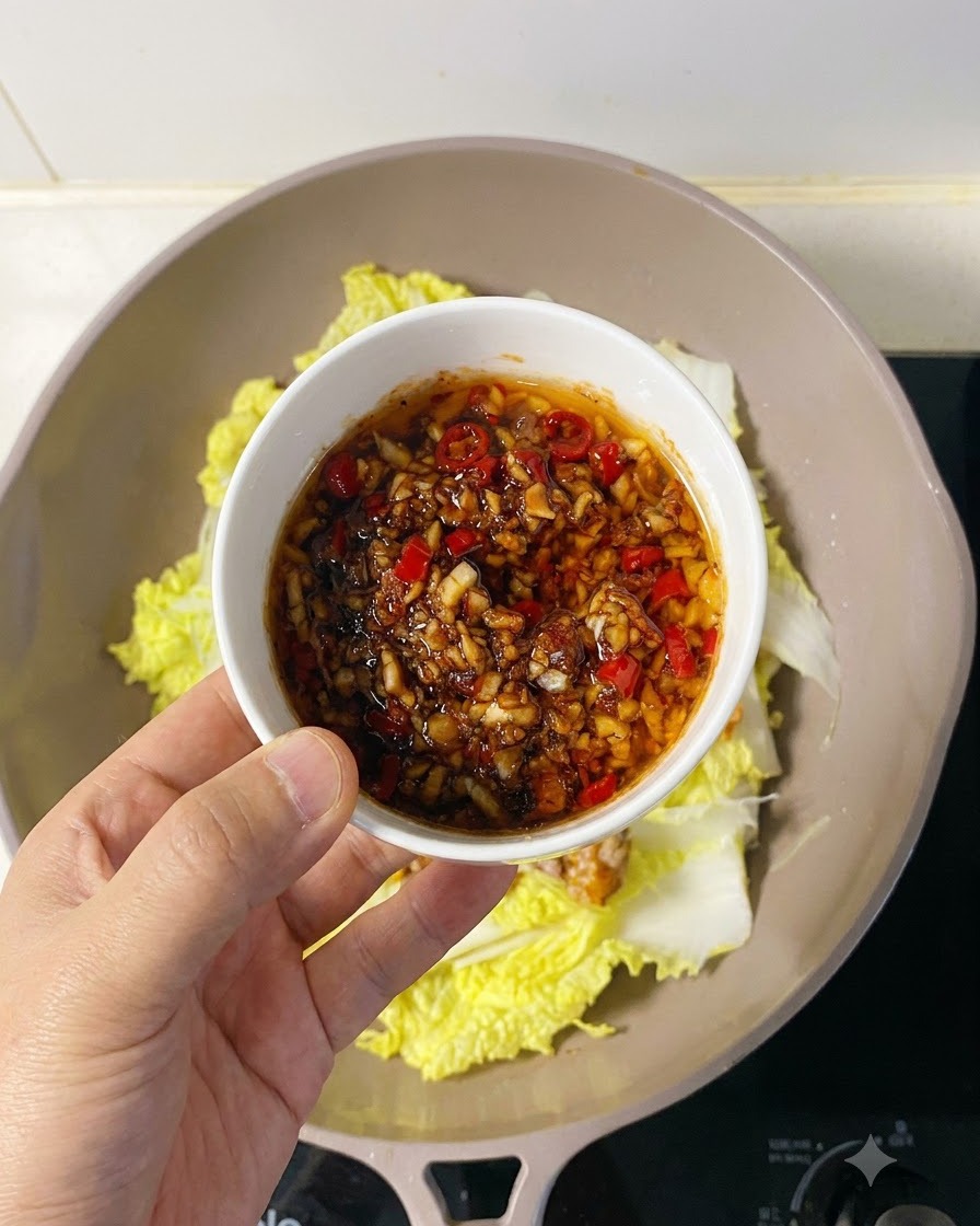 Savory garlic and chili sauce being spooned generously over the arranged scallop meat.