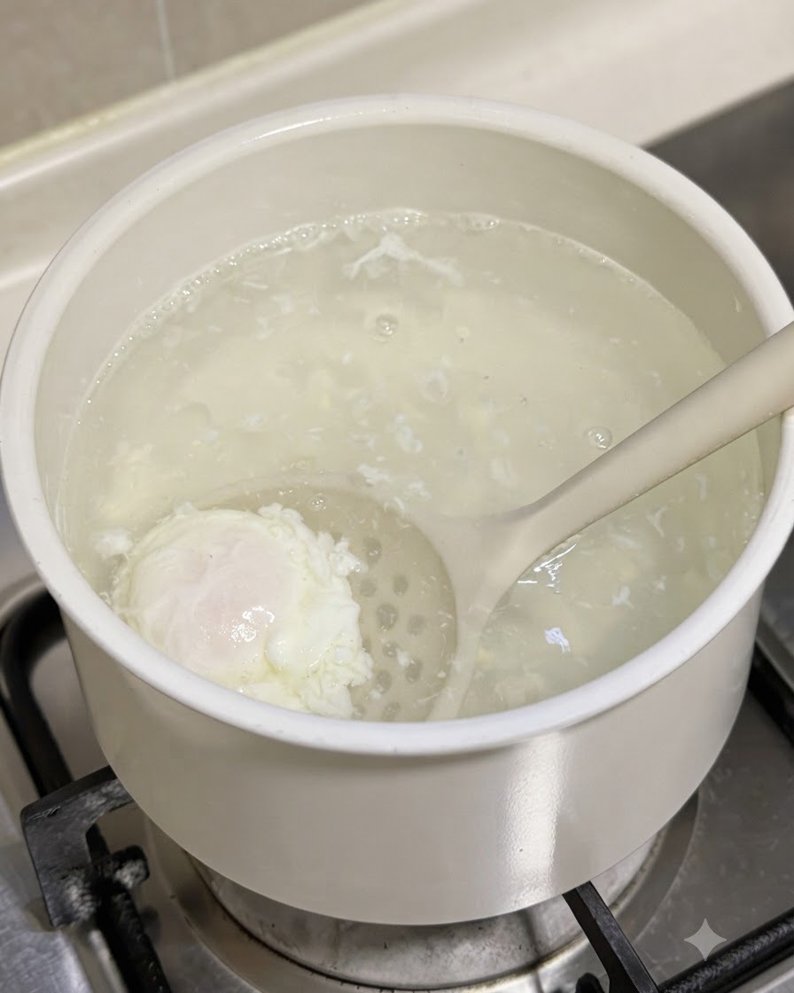 A poached egg being lifted out of a pot of simmering water using a slotted spoon.