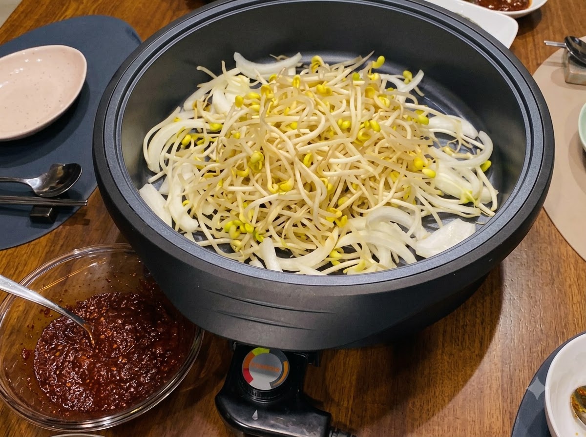 A pile of fresh yellow-tipped bean sprouts layered inside the electric skillet over the onions.