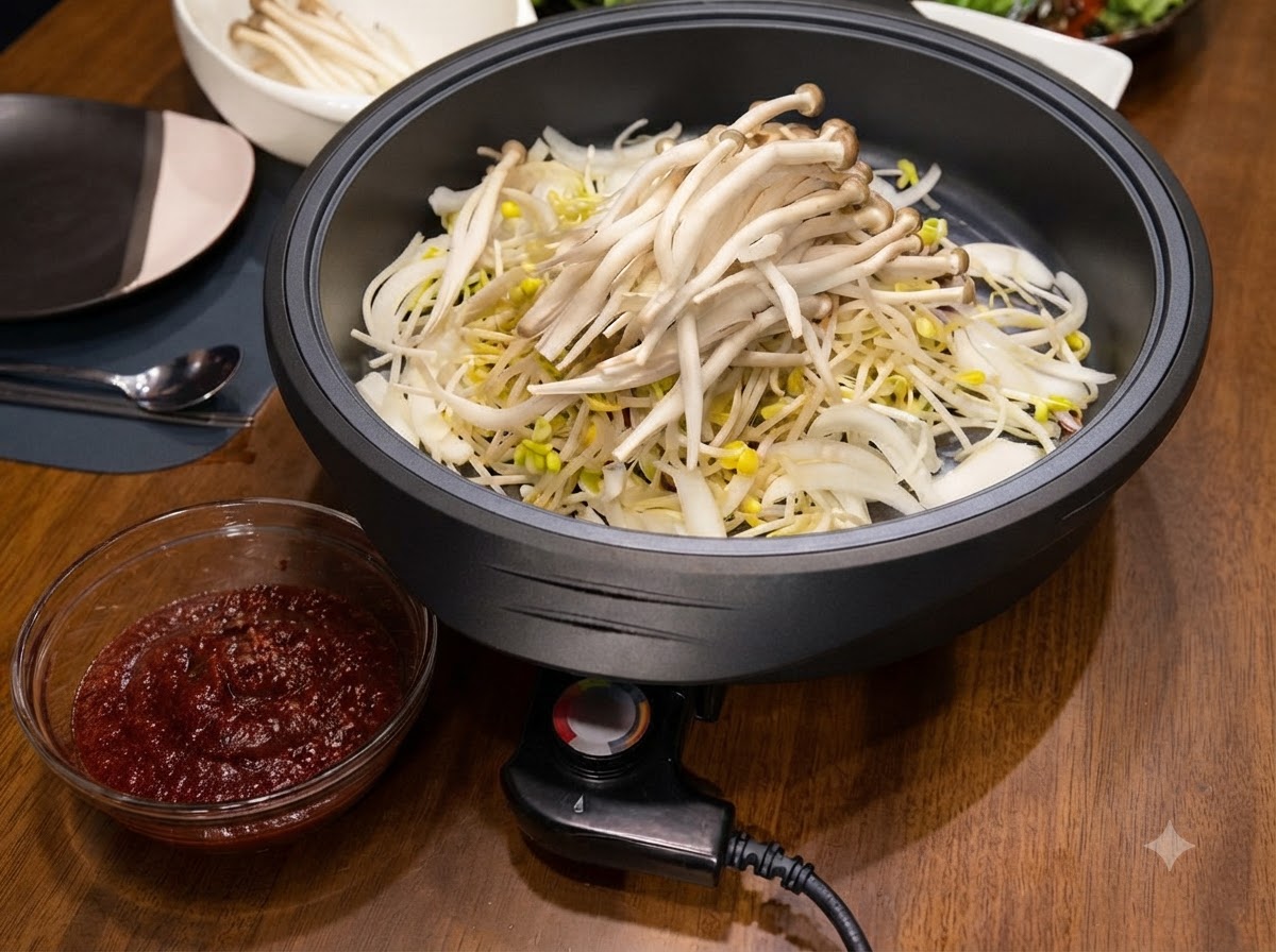 White shimeji mushrooms piled on top of the bean sprouts and onions inside the electric skillet.