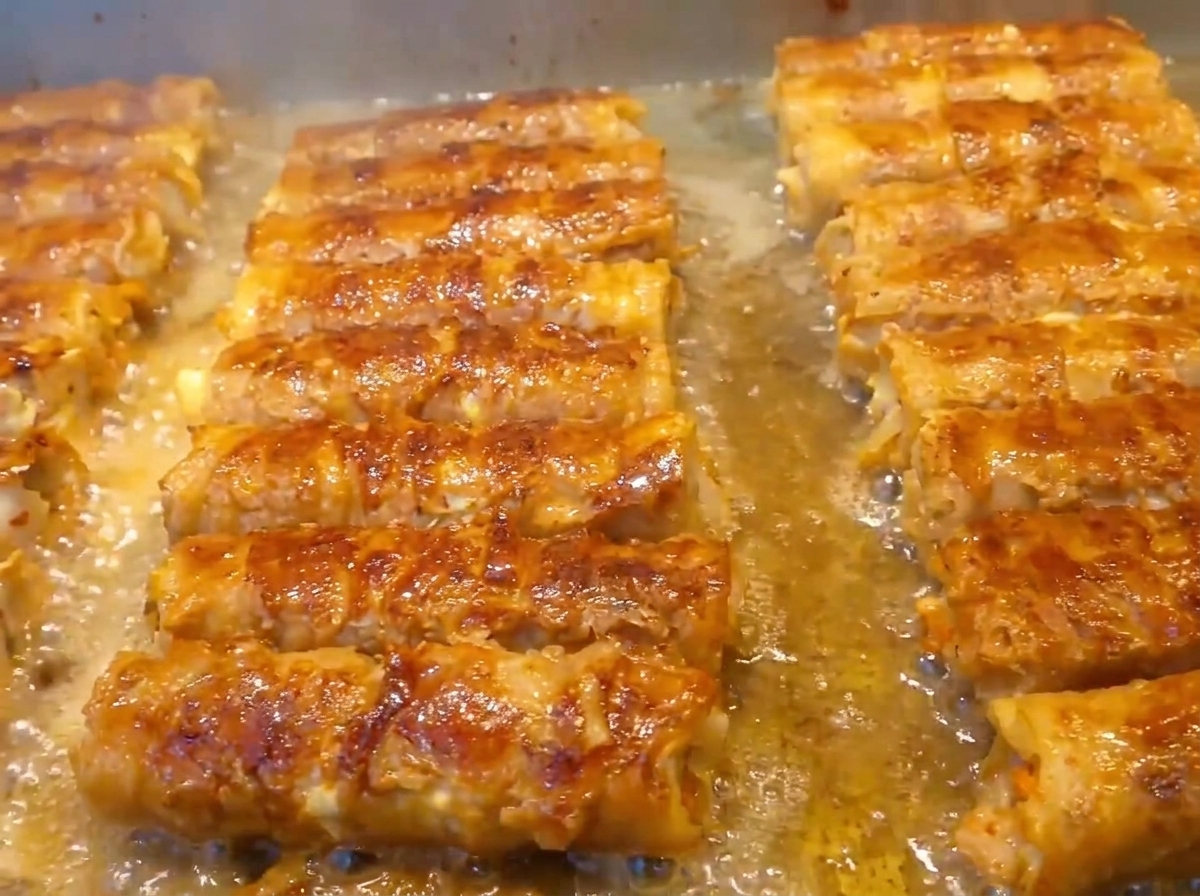 Hands firmly rolling the layered pork belly and fillings into a tight cylindrical shape.