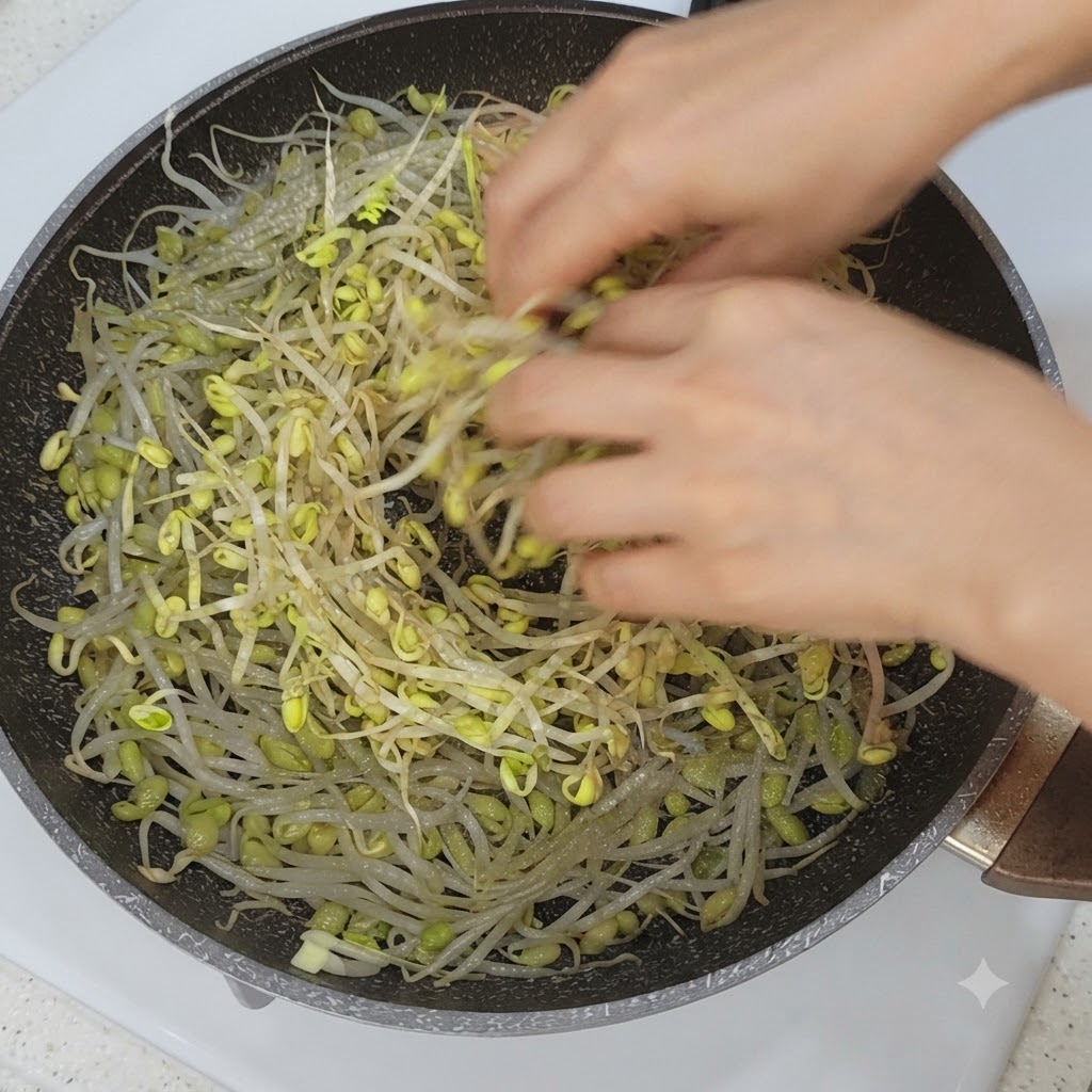 Vegetables and pork belly slices being arranged on top of bean sprouts in a pan.